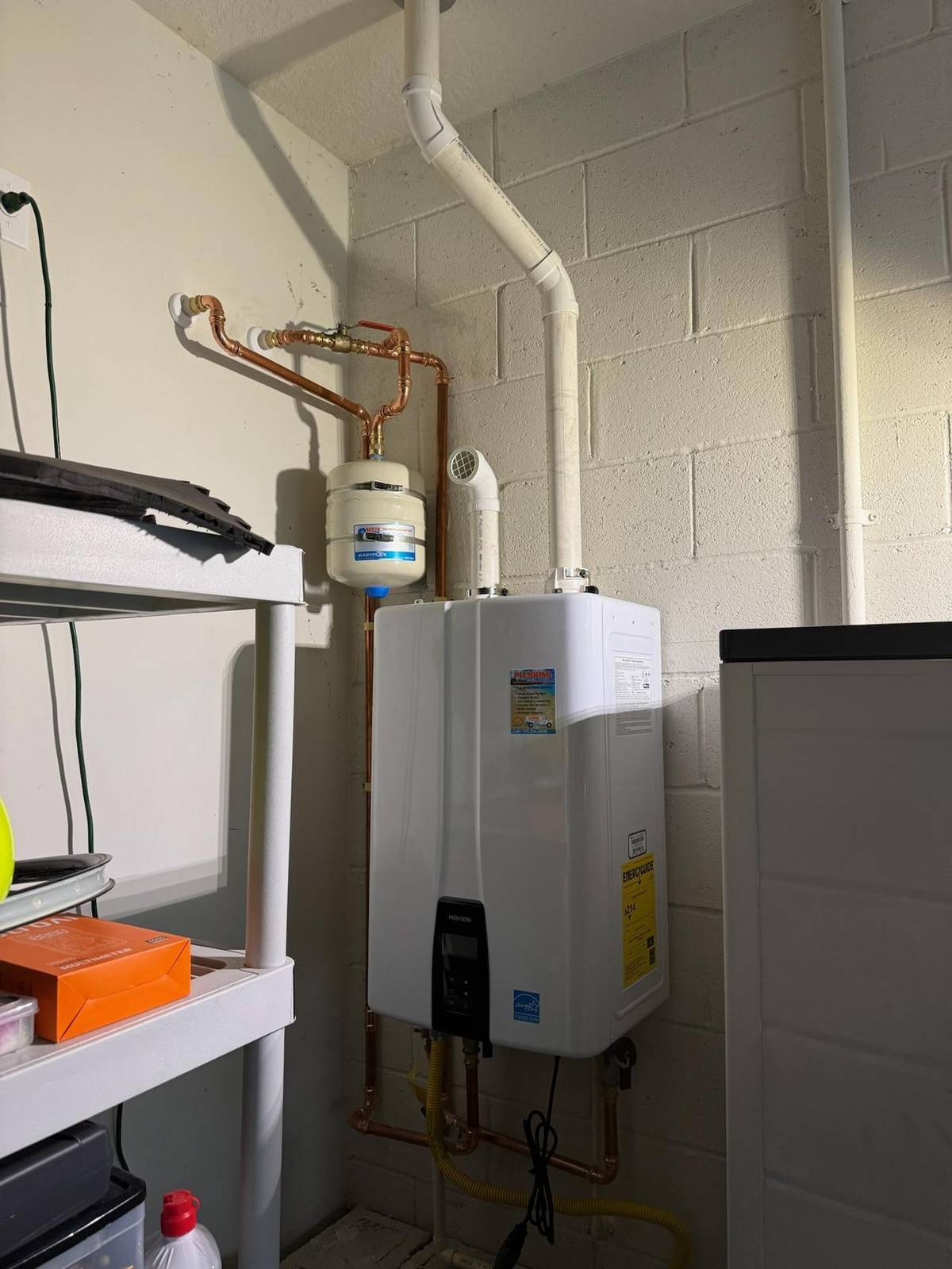 Licensed plumber repairing a water heater in a Palm City, FL home